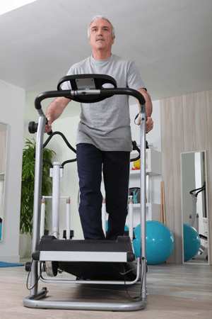 Older man exercising on treadmill in fitness studio with yoga balls and gym equipment