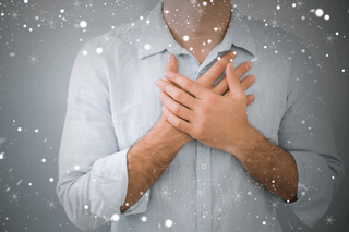 Person in a light shirt holding chest, symbolizing heartburn or acid reflux symptoms