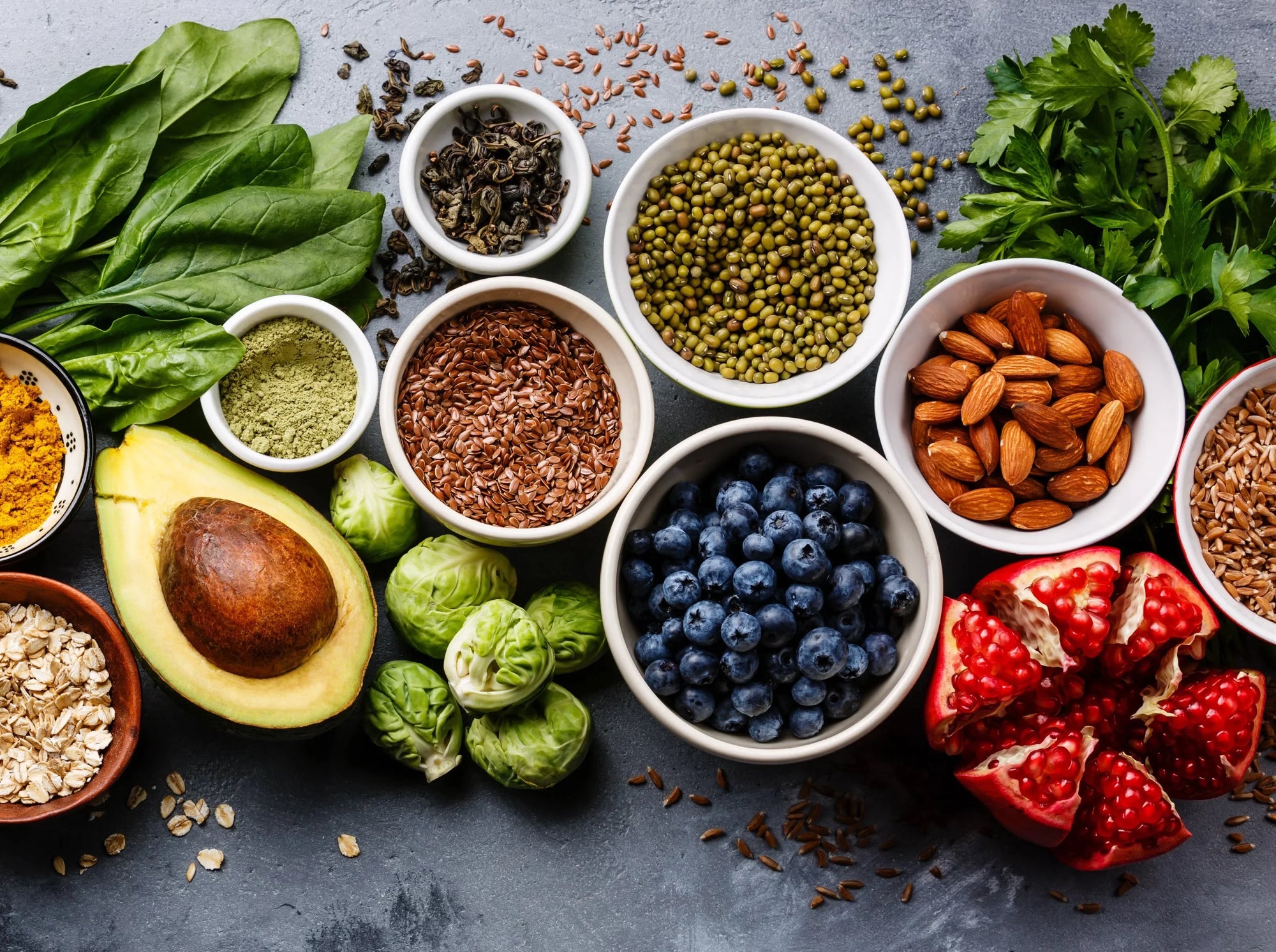 Assorted superfoods including avocado, blueberries, almonds, greens, seeds, and pomegranate